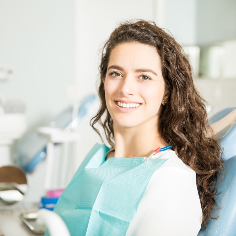 Portrait of smiling young woman sitting on chair at dental clinic